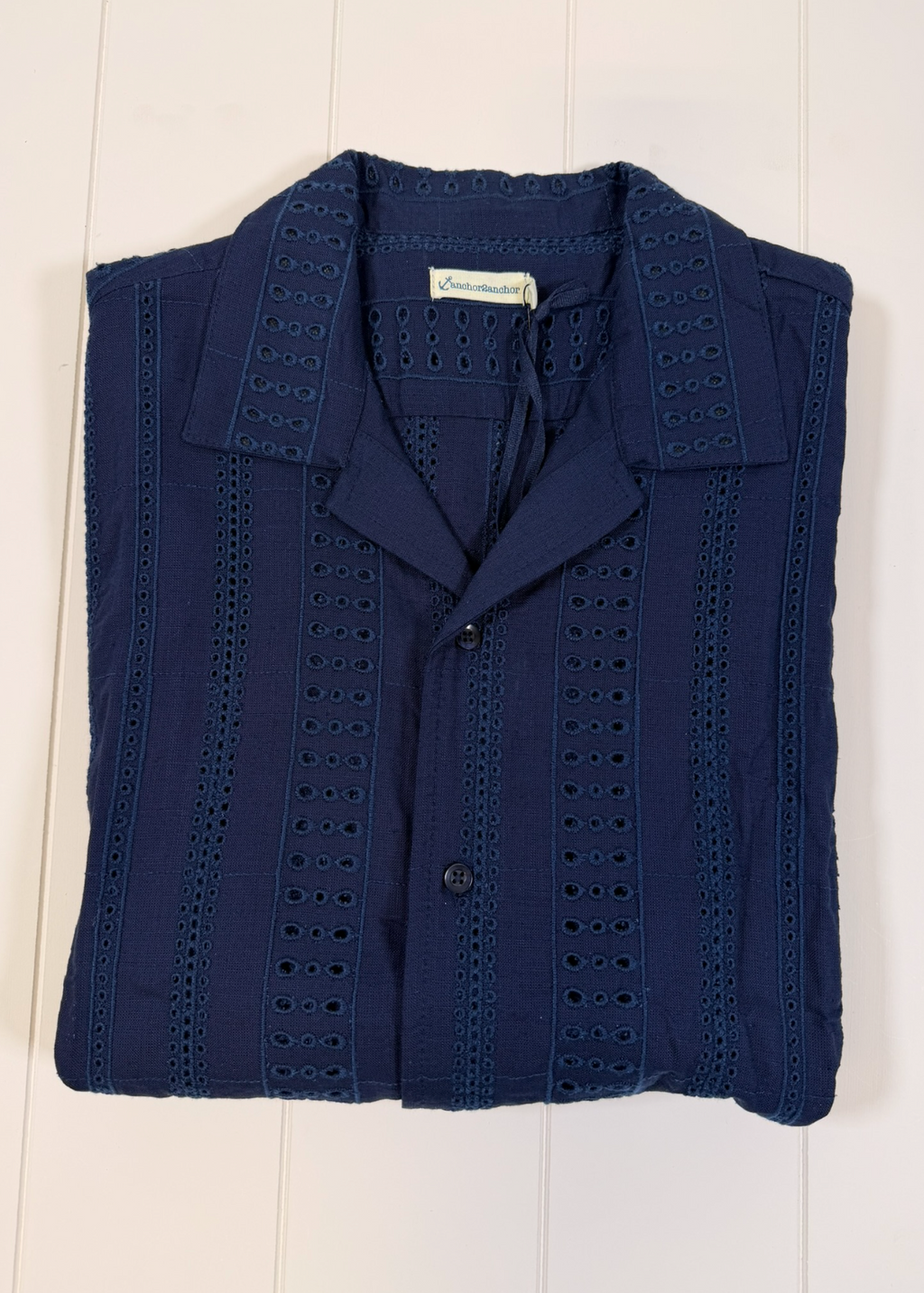Folded navy blue shirt with button details on a white wooden surface