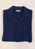 Folded navy blue shirt with button details on a white wooden surface