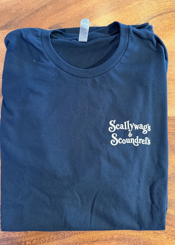 A folded navy blue t-shirt with 'Scallywags & Scoundrels' printed in white gothic-style lettering on the left chest, laid flat on a wooden surface.