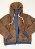 A brown sherpa fleece zip-up hoodie jacket with a blue inner lining, cream-colored drawstrings, and a small white logo patch on the lower left pocket, laid flat on a white wood background.