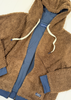 A brown teddy fleece zip-up hoodie jacket layered over a blue zip-up sweatshirt. The outer fleece has cream-colored drawstrings, and a small embroidered logo patch is visible near the lower left pocket.