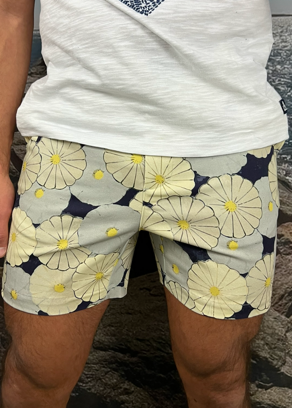 Person wearing floral shorts with a white shirt on a rocky surface