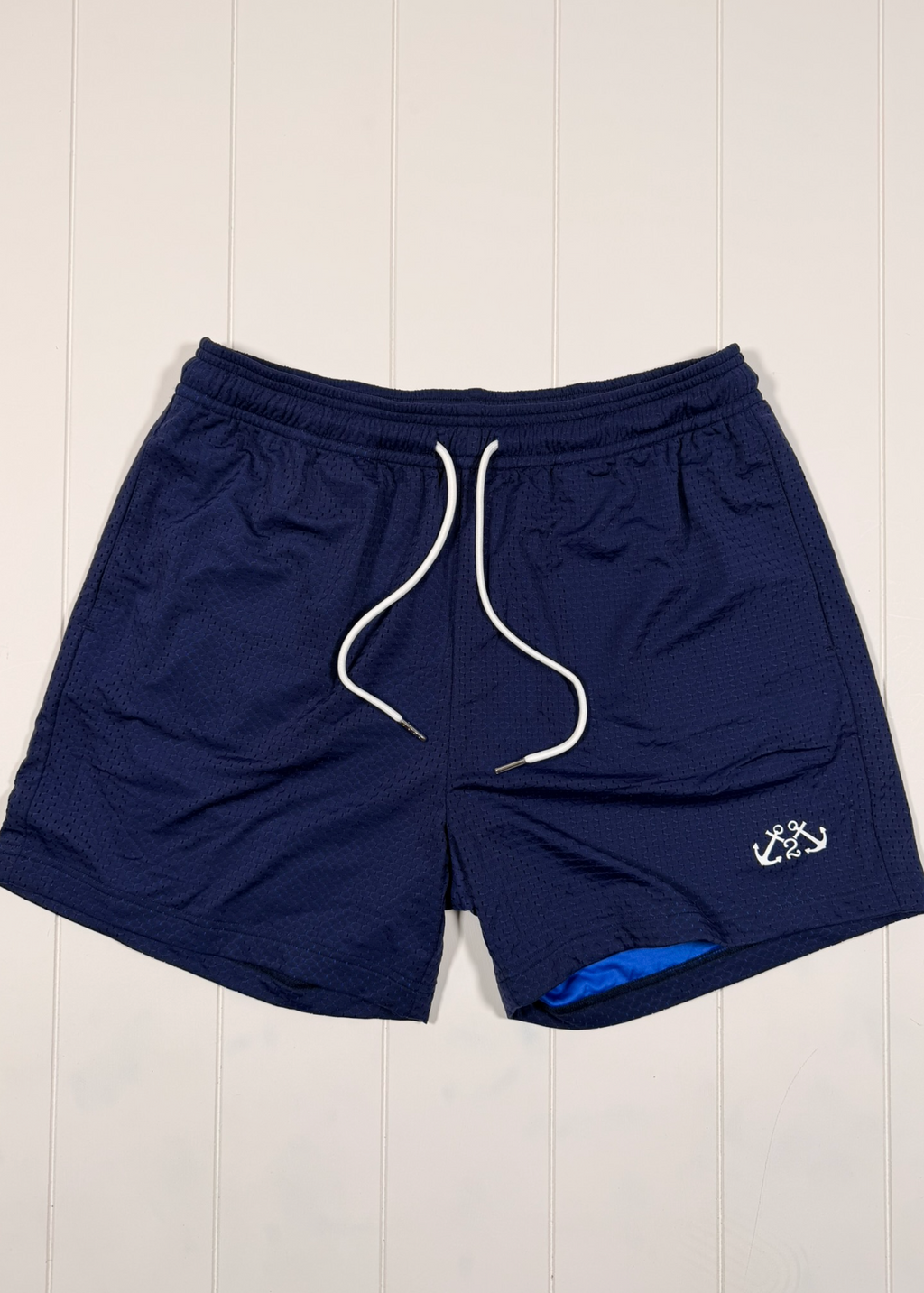 Navy blue shorts with a white drawstring on a light wooden floor.