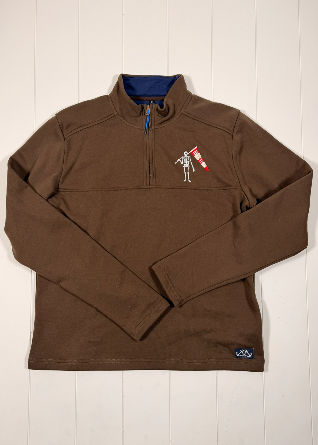 Brown pullover with a small logo on a white wooden surface