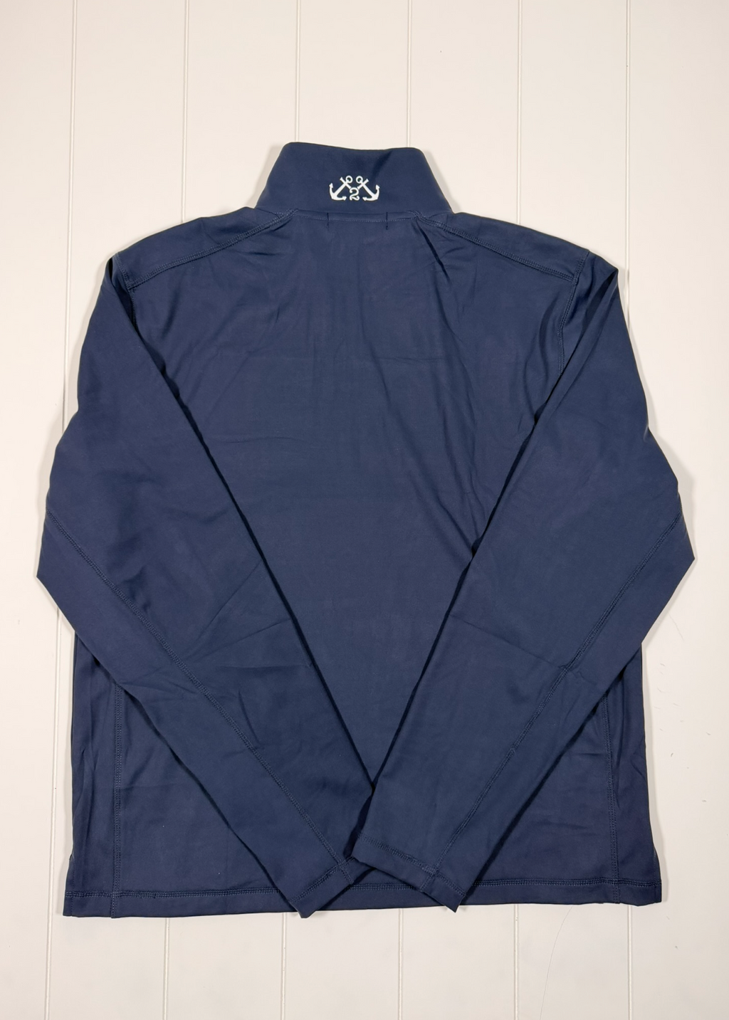 Navy blue pullover with a brand logo on a white wooden background