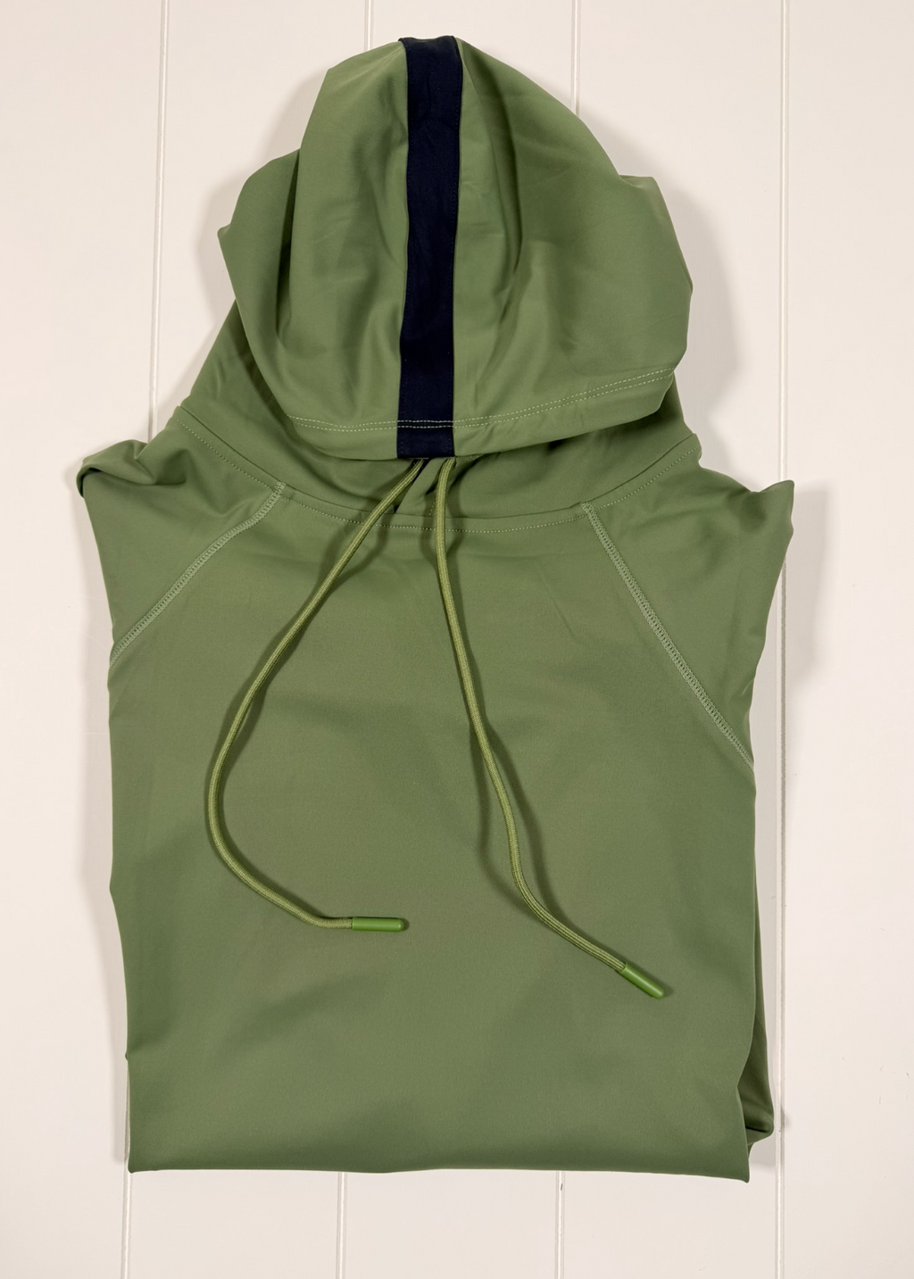 Green sleeveless hoodie with a hood on a white wooden surface