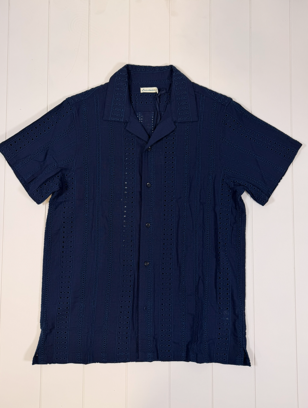 Navy blue short-sleeve shirt on a white wooden surface