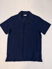 Navy blue short-sleeve shirt on a white wooden surface