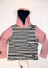 A children's hooded long-sleeve top laid flat on a white wood background. The front has horizontal black and white stripes, while the hood, inner lining, and sleeves are light pink.