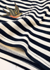 Close-up of a navy and cream striped knit garment with a small embroidered swallow motif near the upper left area.