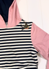 A close-up of a hooded top with a navy and white striped body, pink hood and sleeve, and a small embroidered swallow motif near the collar.