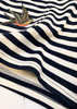 Close-up of a navy and off-white striped knit fabric with a small embroidered swallow motif near the upper left area.