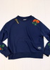 A navy blue crewneck sweatshirt with embroidered orange roses and green leaves on the shoulders and cuffs, featuring yellow 'Stans' embroidery on the left shoulder and a small circular logo patch on the right sleeve, laid flat on a white wood background.