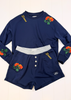 A navy blue two-piece loungewear set featuring a long-sleeve top and matching shorts. The top has yellow 'Stories' embroidery on the chest, orange rose floral patches on the shoulders and sleeves, and a contrasting light gray elastic waistband.