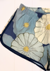 A close-up of a pair of sheer mesh shorts featuring a floral print with large light blue, cream, and navy flower motifs, accented with yellow centers and dark navy trim.