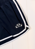 Close-up of navy blue athletic shorts with white side stripes and a white anchor logo near the hem, laid against a white paneled background.