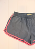 Gray athletic shorts with pink piping trim along the side seams and hem, laid flat on a white paneled background.