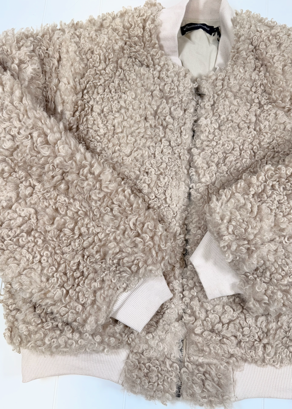 A beige curly sherpa fleece zip-up jacket with ribbed cream cuffs and collar, laid flat on a white background.