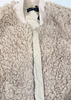 Close-up of a cream-colored sherpa fleece jacket with a quilted front zipper and ribbed collar.