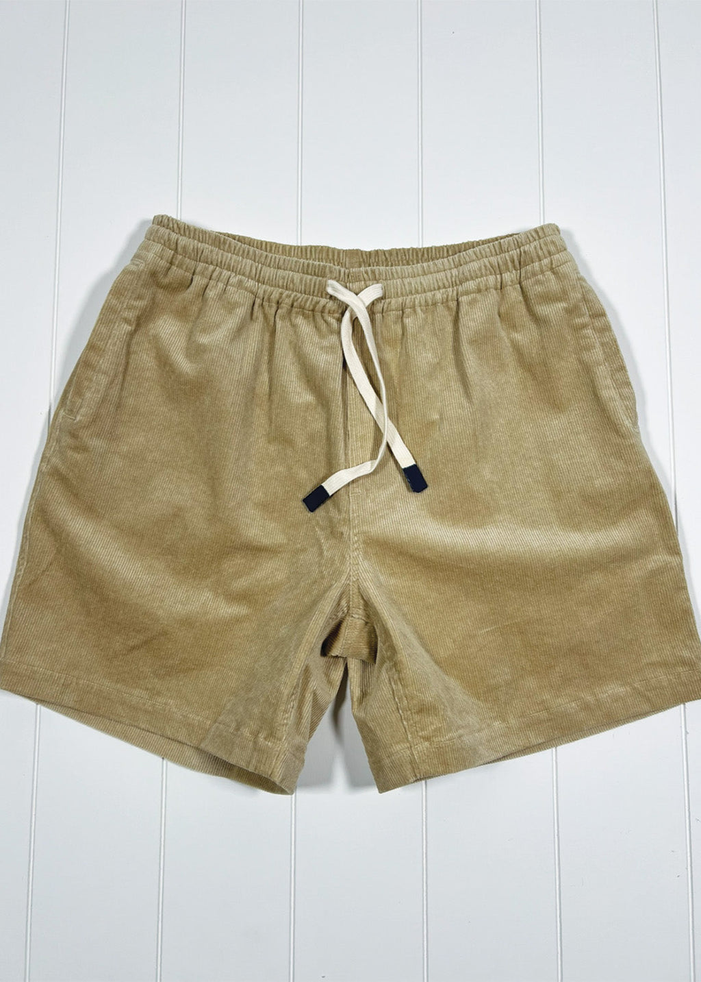 Beige shorts with a drawstring on a white wooden background