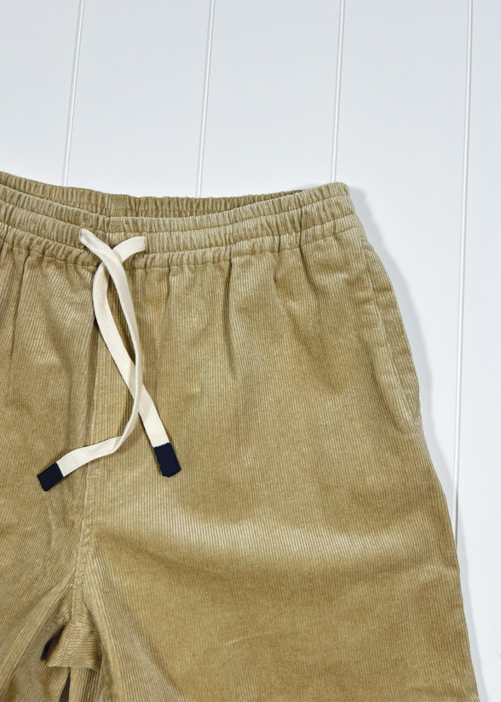 Beige corduroy shorts with a drawstring on a white background