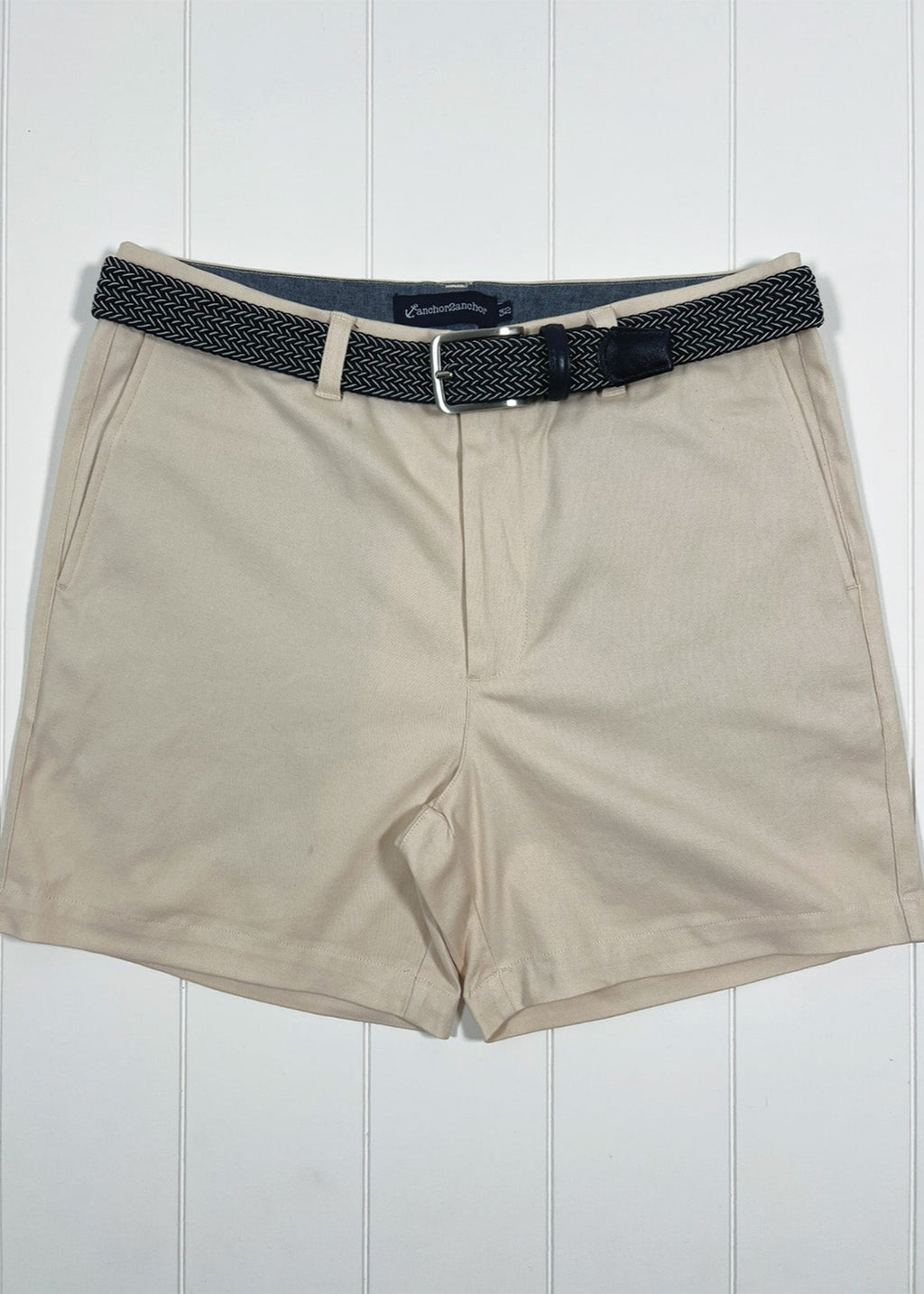 Beige shorts with a black belt on a white wooden background