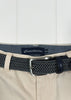 Navy belt with woven pattern and silver buckle on beige pants, brand label visible.