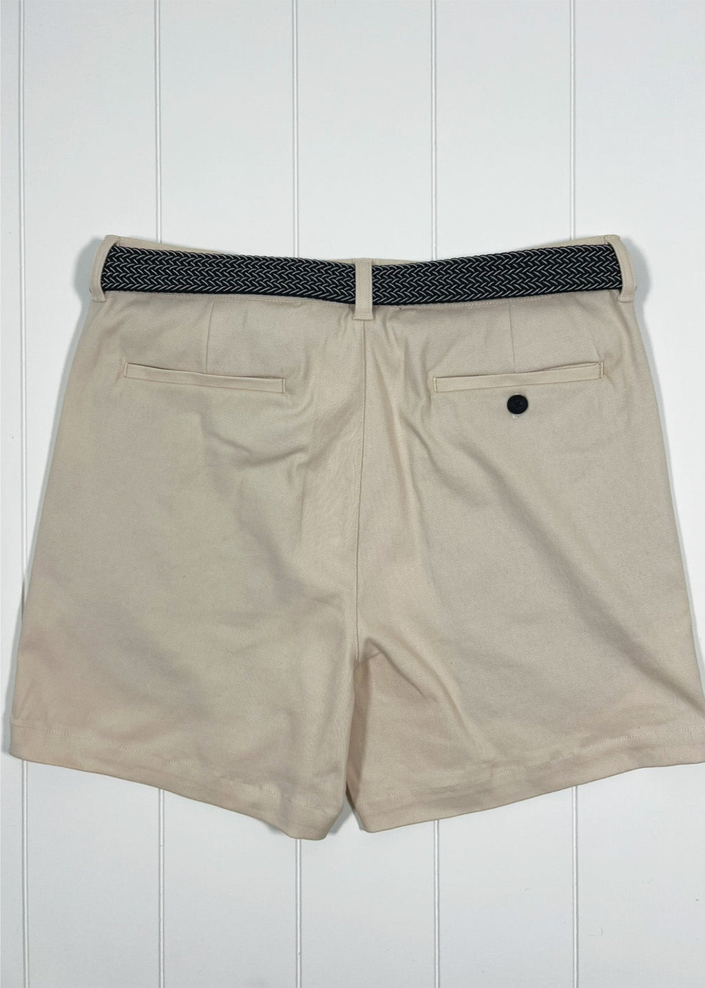 Beige shorts with a black belt on a white wooden background