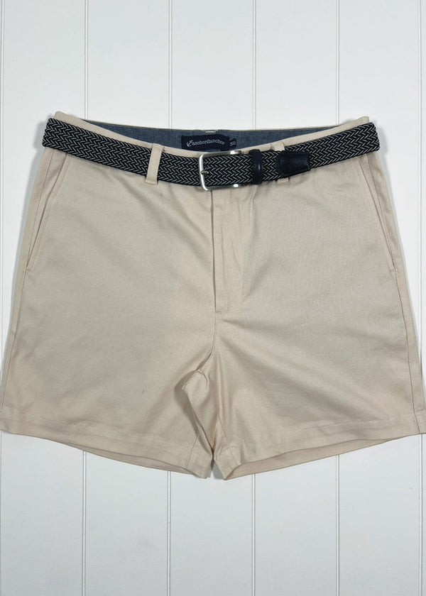 Beige shorts with a black belt on a white wooden background