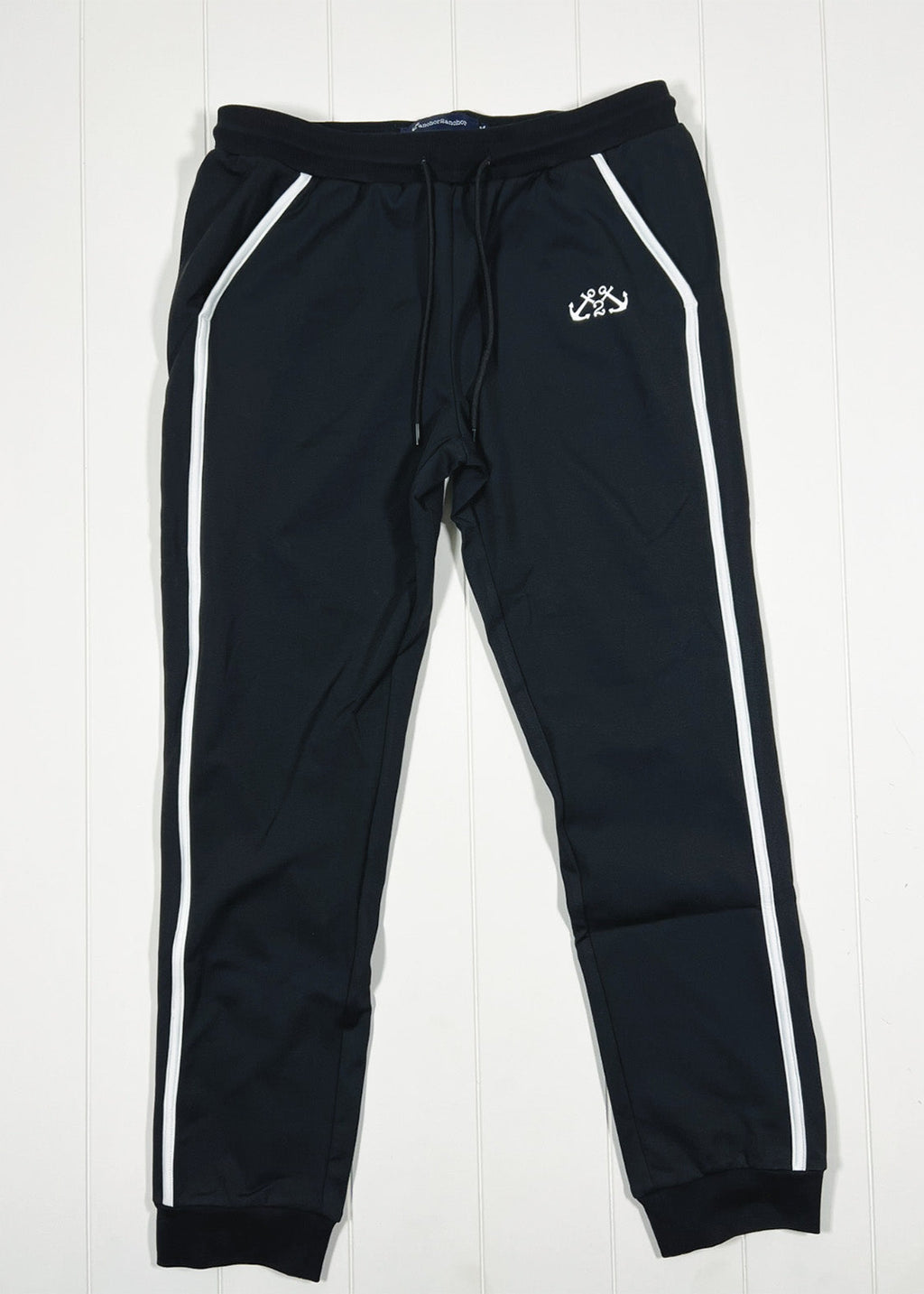 Black tracksuit pants with white stripes on a white background