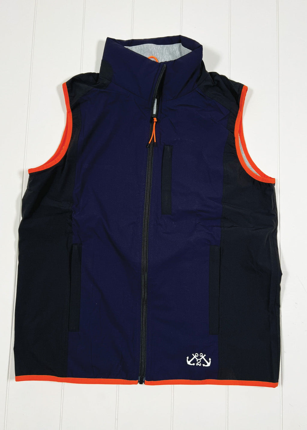 Navy blue vest with orange trim on a white wooden background