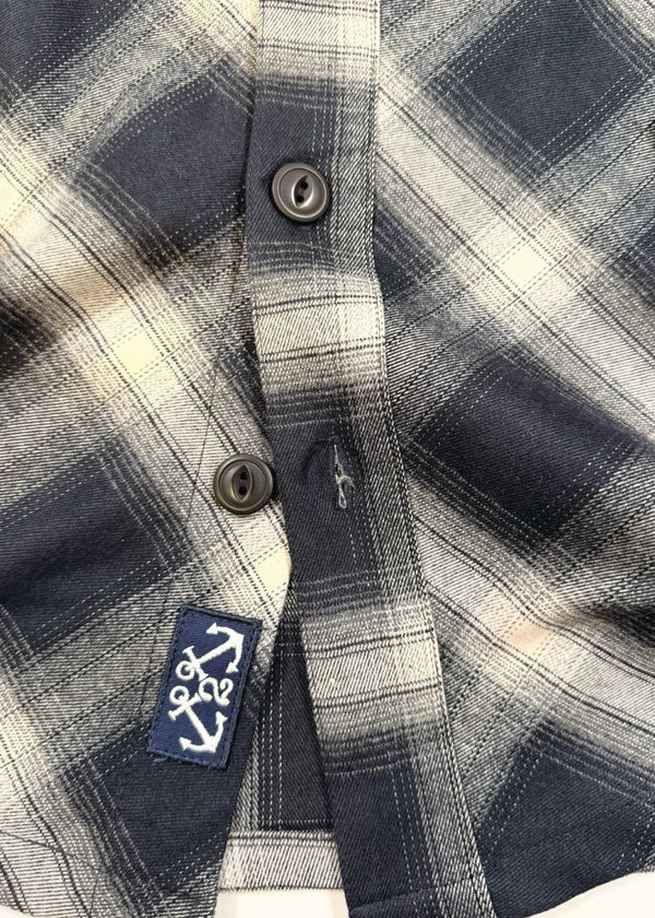 Close-up of a plaid shirt with a brand logo on a white background