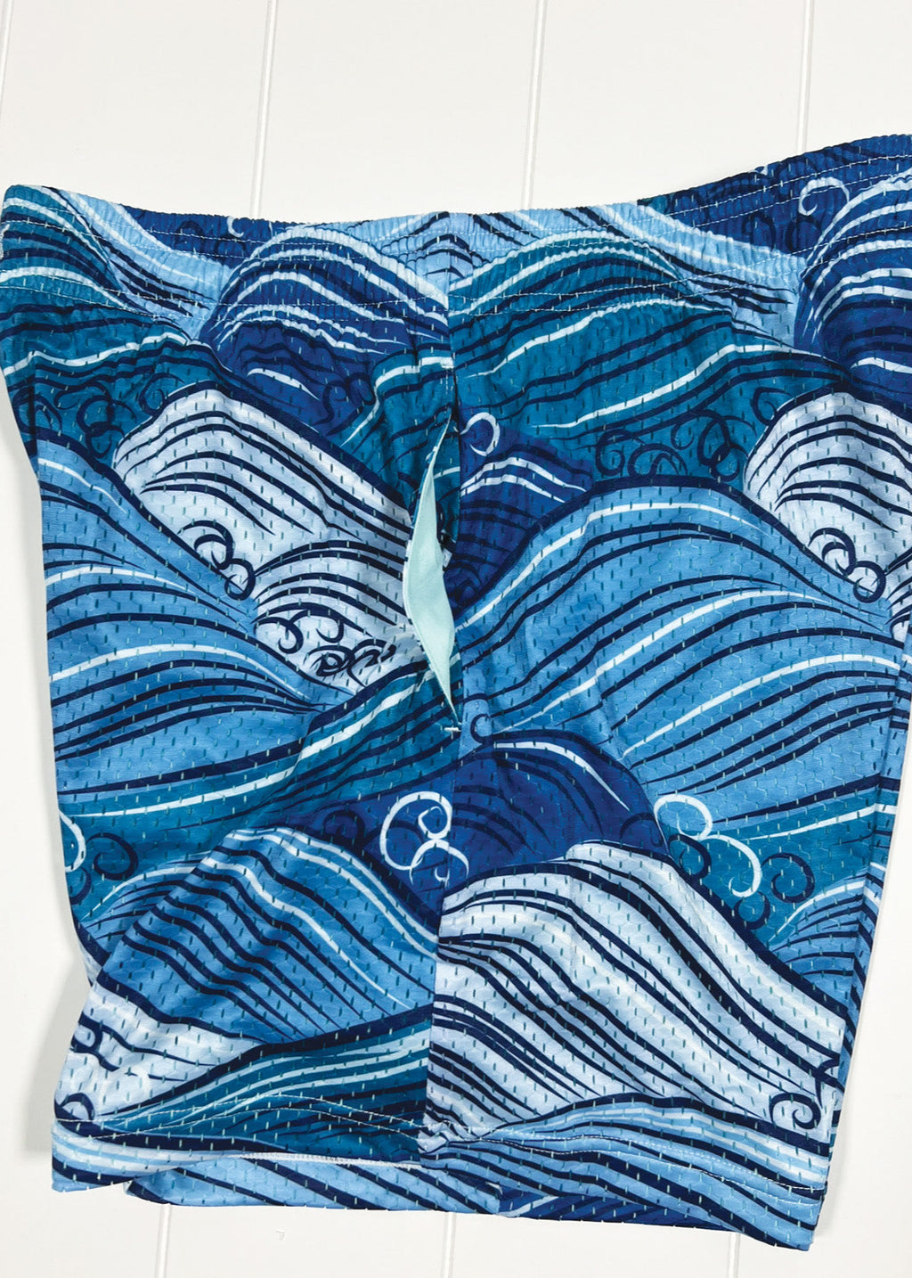 Blue wave-patterned shorts on a white background