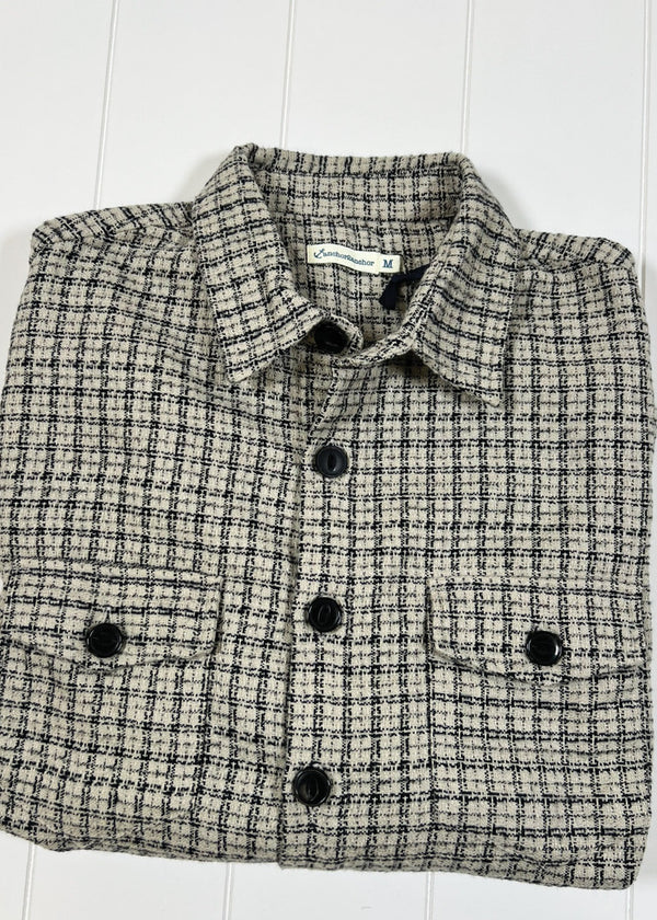 Folded checkered shirt with black buttons on a white wooden surface