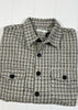 Folded checkered shirt with black buttons on a white wooden surface