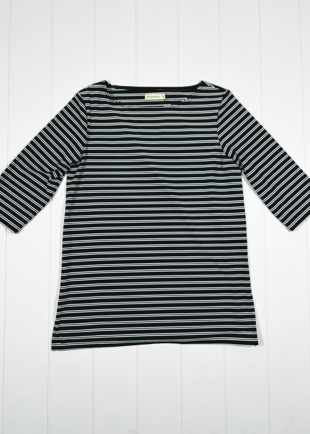 Black and white striped long-sleeve top on a white wooden background