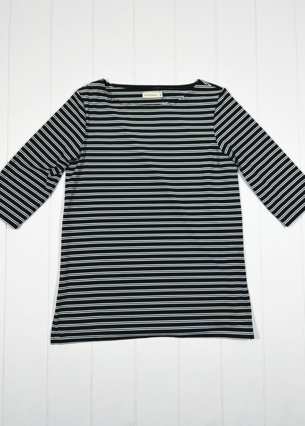 Black and white striped long-sleeve top on a white wooden background