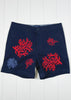 Navy shorts with red and blue coral designs on a white wooden background