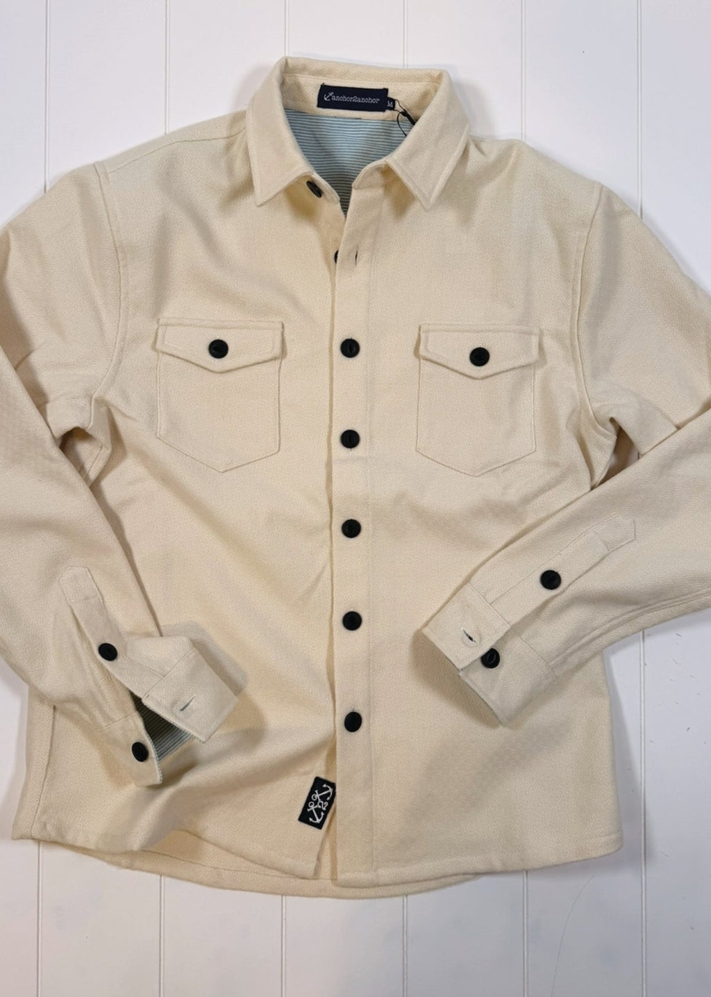 Beige jacket with black buttons on a white background