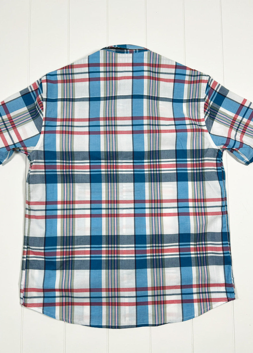 Plaid shirt with short sleeves on a white wooden background