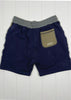 Navy shorts with a gray waistband and green pocket on a white wooden background