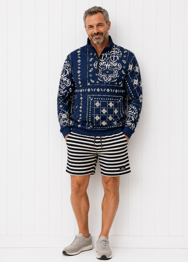 Man wearing a patterned navy hoodie and striped shorts against a white background