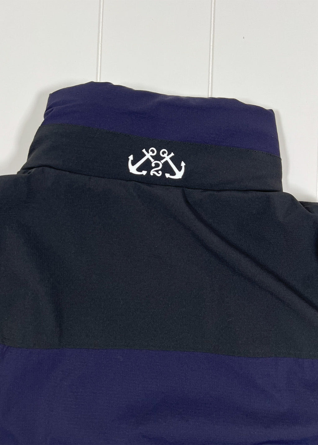 Navy and black jacket with an embroidered anchor on a white background