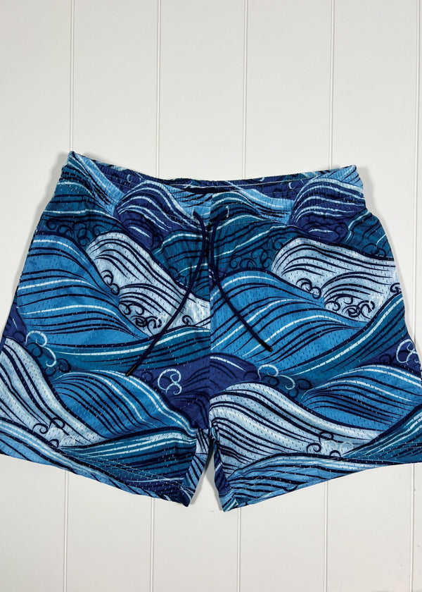 Blue wave-patterned shorts on a white wooden background