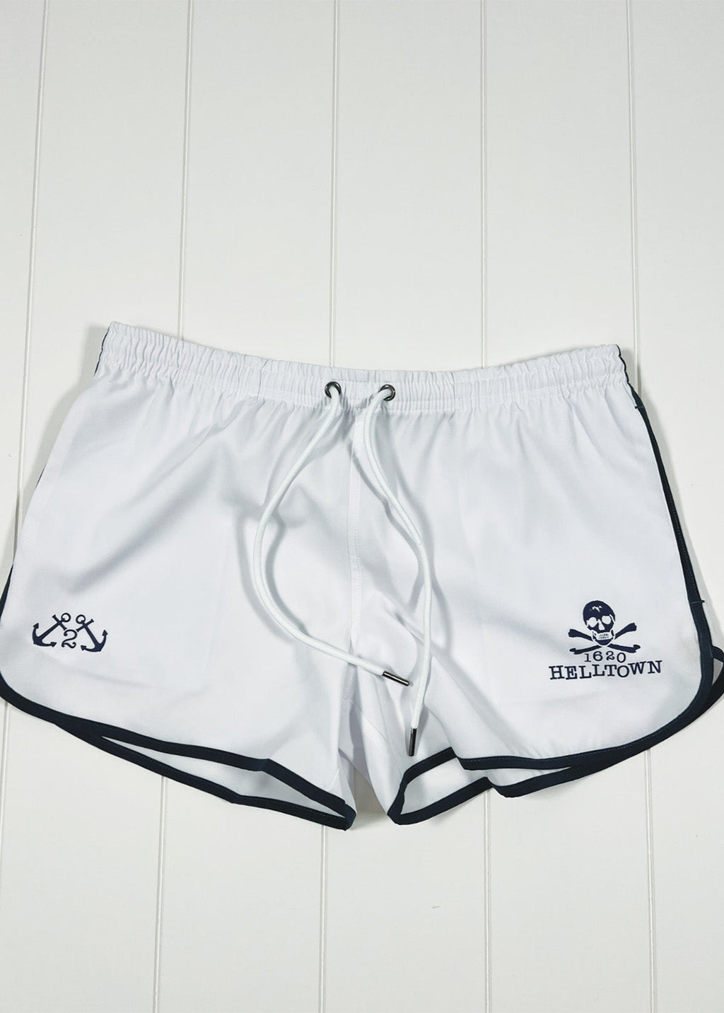 White shorts with black trim and logos on a white wooden background