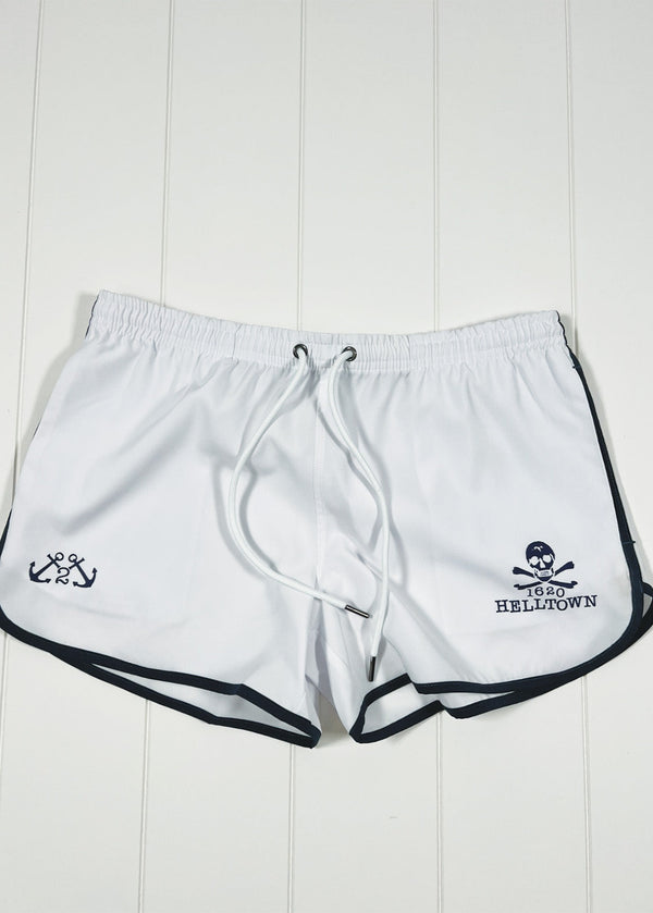 White shorts with black trim and logos on a white wooden background